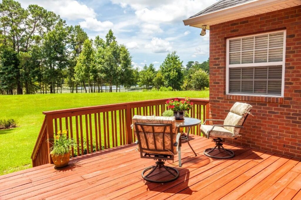 Timber deck with outdoor table and chairs attached to a brick home