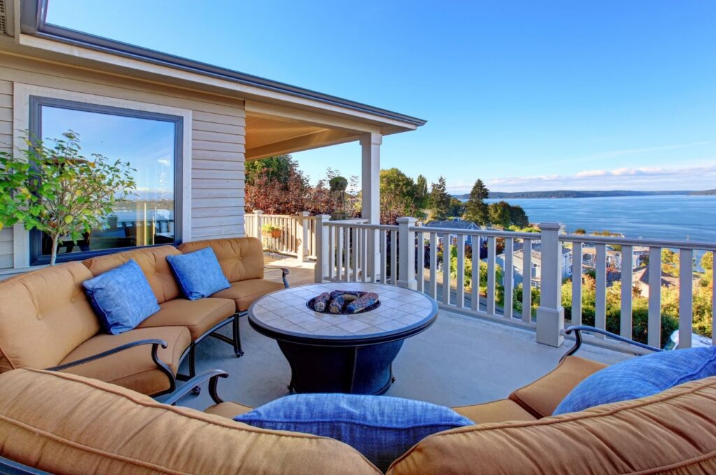 Covered patio deck with outdoor lounge seating overlooking a waterfront view