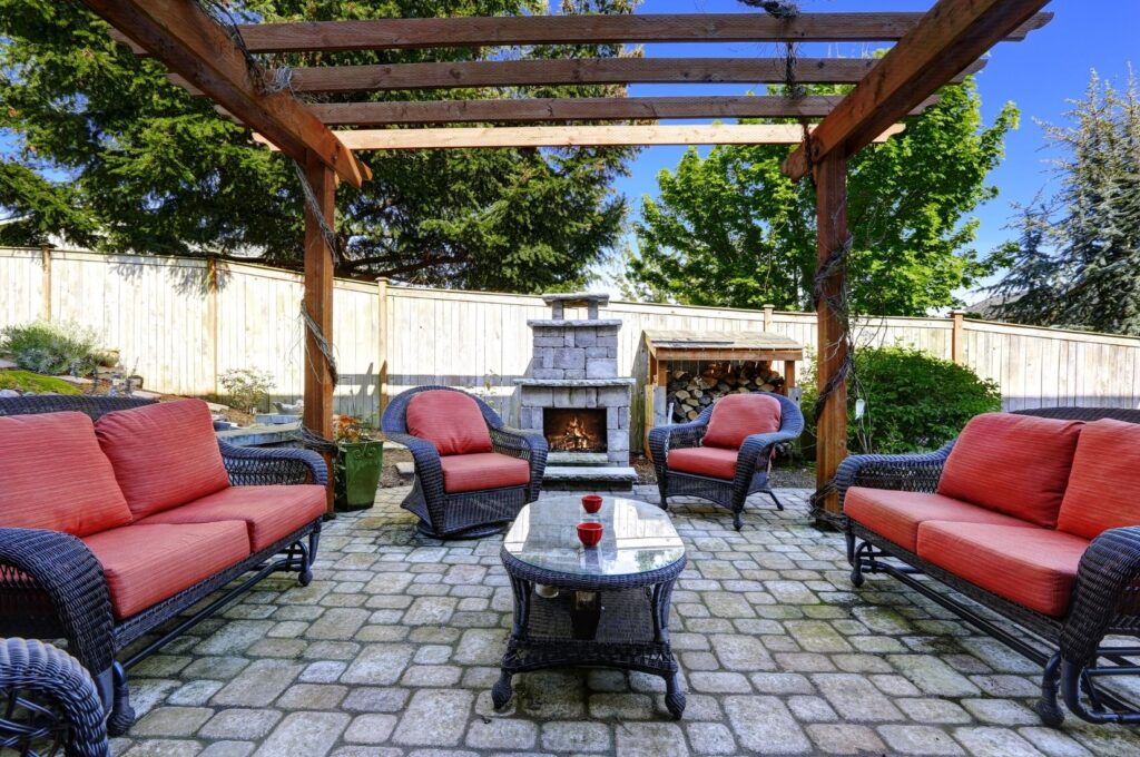 Timber pergola over a paved outdoor patio with lounge seating and an outdoor fireplace