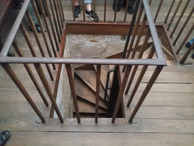Visitors looking down a narrow spiral staircase inside the Hobart Convict Penitentiary