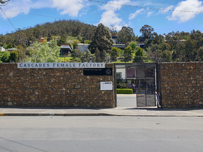 Stone perimeter wall and entrance gate of the Cascades Female Factory Historic Site, with hills in the background