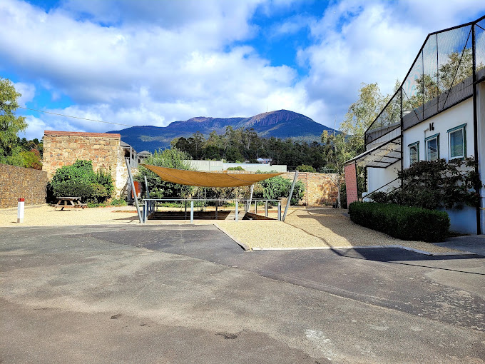 Courtyard at the Cascades Female Factory Historic Site with a shade sail over picnic tables and Mt Wellington behind