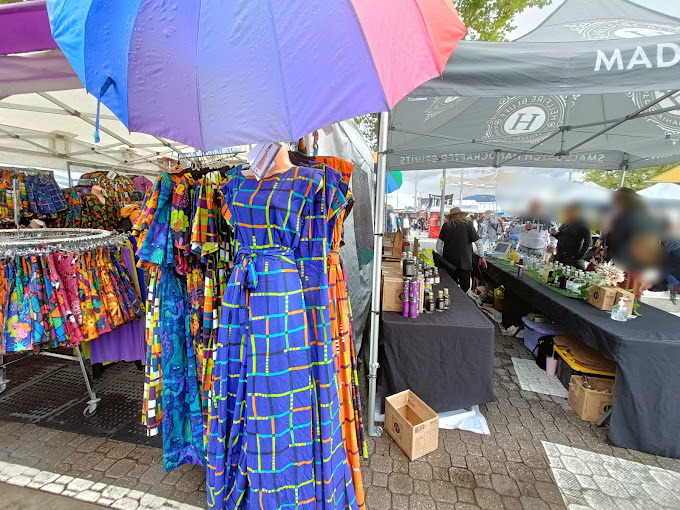 Colourful printed dresses on display under a rainbow umbrella at a Salamanca Market clothing stall